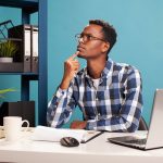 A professional working thoughtfully at a laptop, reflecting on how digital systems shape modern writing and communication.