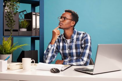 A professional working thoughtfully at a laptop, reflecting on how digital systems shape modern writing and communication.