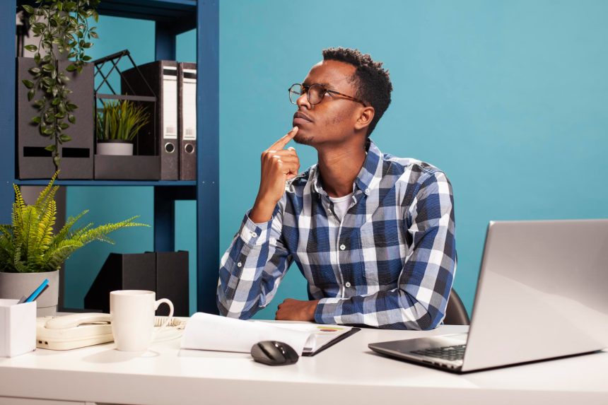 A professional working thoughtfully at a laptop, reflecting on how digital systems shape modern writing and communication.