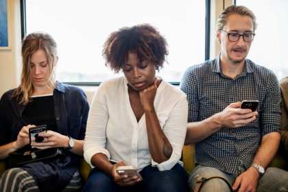 A diverse group of commuters on a train, each absorbed in their smartphones