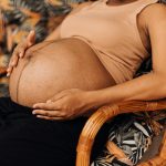Pregnant woman sitting calmly with hands on her belly, reflecting on emotional wellbeing during pregnancy