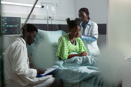 African medical team examining a patient in a hospital ward with monitor and stethoscope