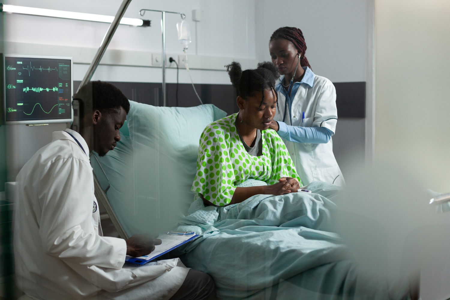 African medical team examining a patient in a hospital ward with monitor and stethoscope