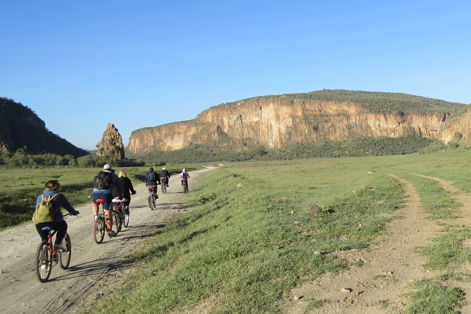 Cyclists riding through the valley at Hell’s Gate National Park with cliffs and open landscape in Kenya